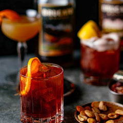 Negroni cocktail in front of Brucato Amaro bottles and snacks