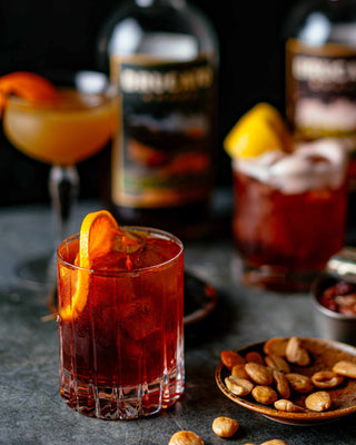 Negroni cocktail in front of Brucato Amaro bottles and snacks