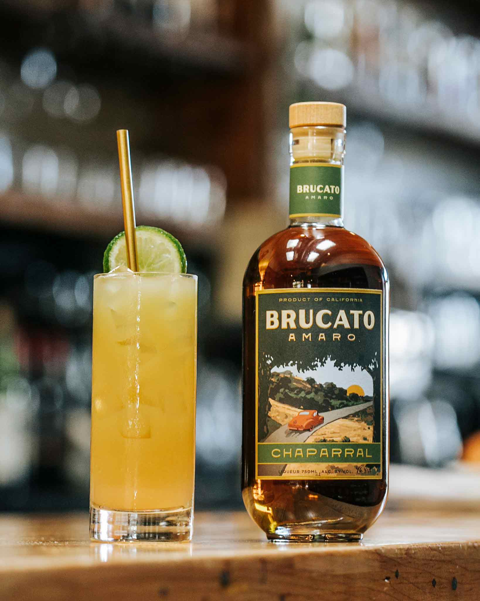 Gamboa Beach cocktail with straw next to bottle of Brucato Amaro Chaparral on bar