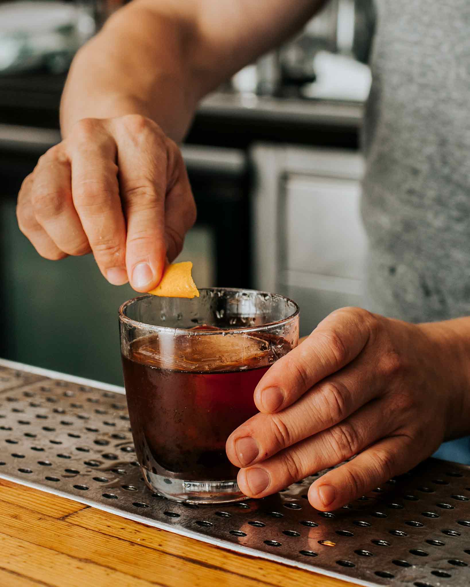 Junction House cocktail in glass with bartender adding orange twist