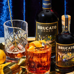 Pinnacle Park cocktail on tray next to bottles of Brucato Amaro Woodlands