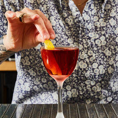 Sycamore Flat cocktail with bartender in pattern shirt placing lemon twist