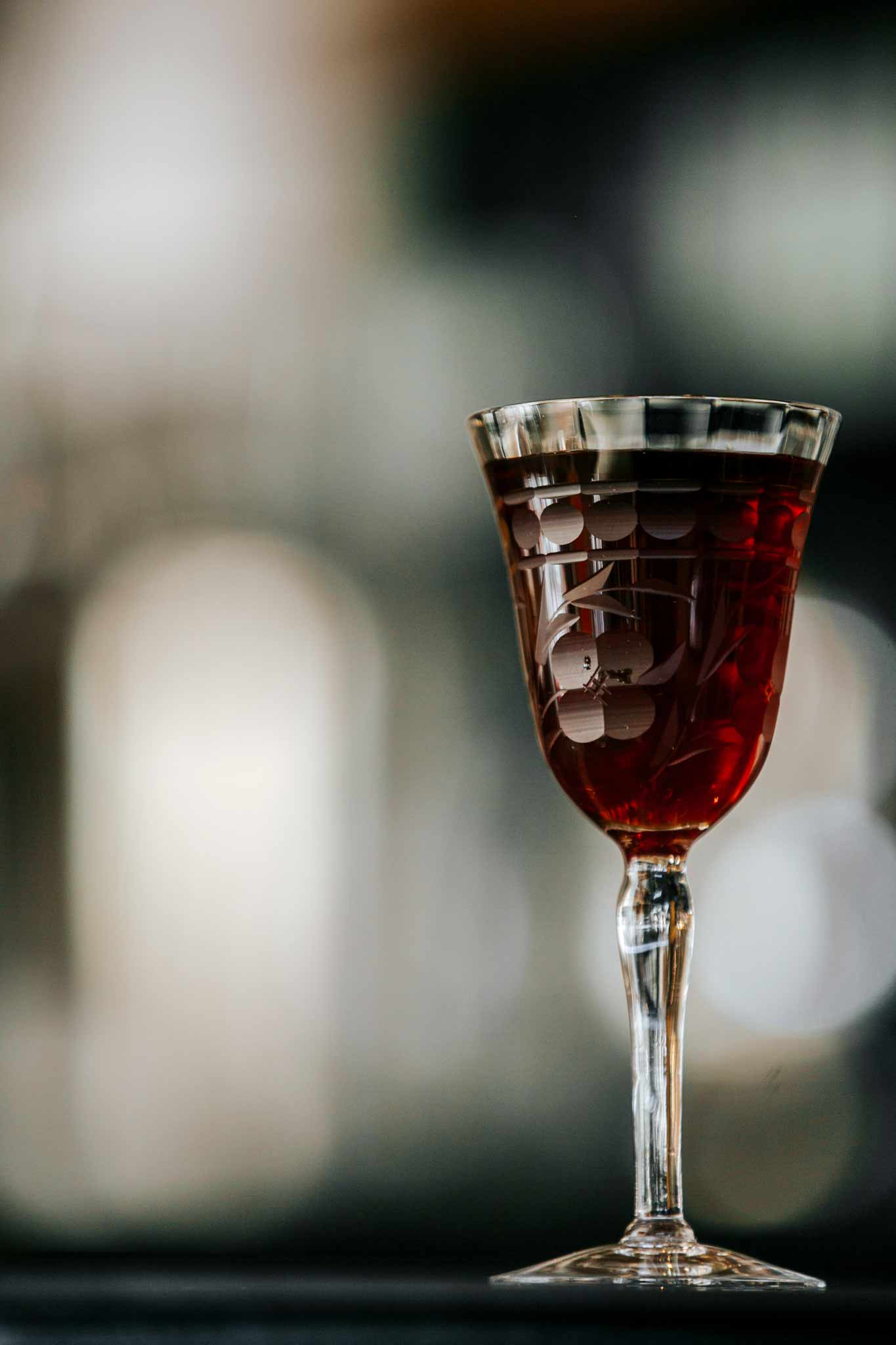 Three Crossing cocktail in cocktail glass in front of blurred background