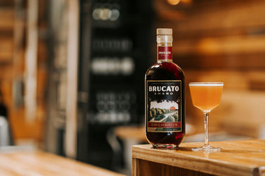 Bottle of Brucato Amaro Orchards and cocktail sitting on bar 