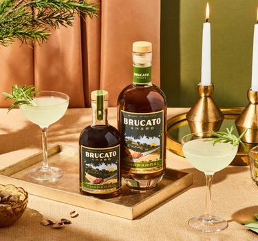 Bottles of Brucato Amaro Chaprral on a table with cocktails and snacks